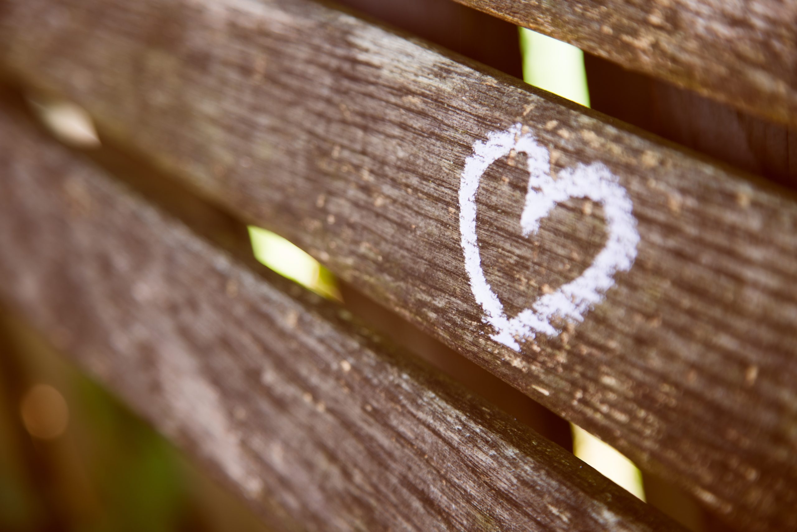 chalk heart drawn on a weathered wooden fence