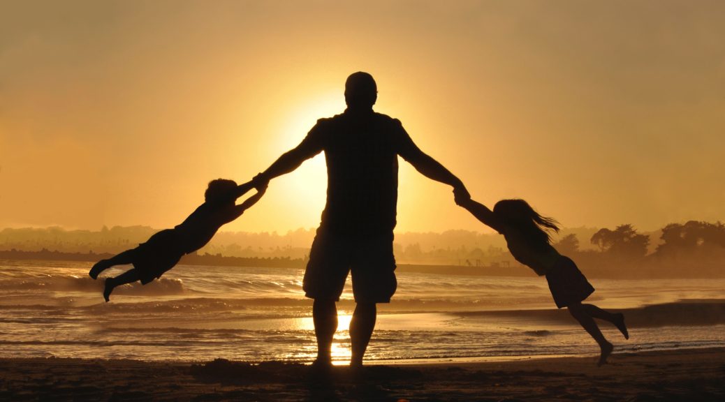 father on beach at sunset with two children