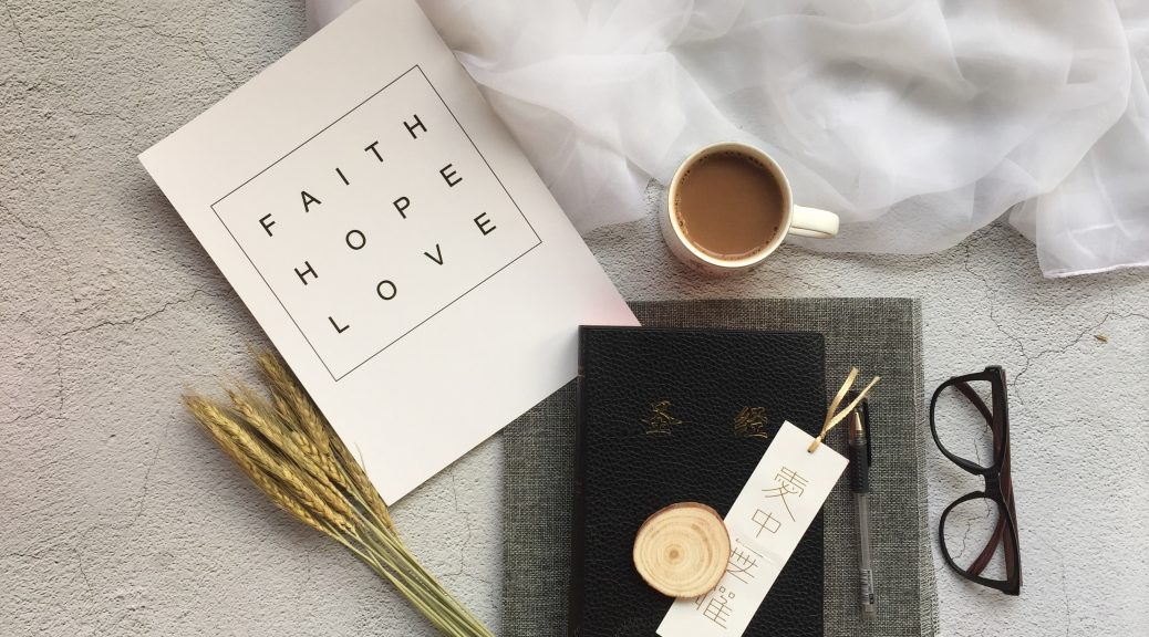 Book with faith, hope and love written on it. Coffee cup and pen