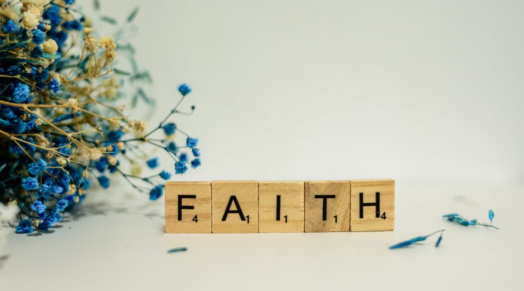 scrabble letters spelling faith with purple flowers